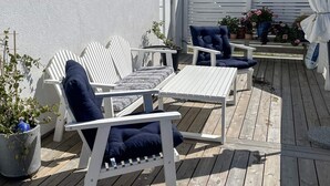 A deck with white furniture, including a sofa and chairs, and potted plants. - 4 Star Holiday Home in Gotlands Tofta (Gotlands Tofta)