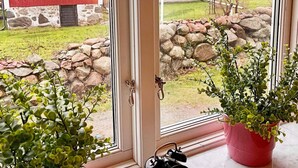 A window with a view of a red house, a stone wall, and a potted plant. - 6 Person Holiday Home in Solvesborg-by Traum (Sölvesborg)