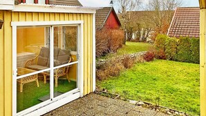 A yellow house with a glass door leading to a patio with two wicker chairs. - 6 Person Holiday Home in Solvesborg-by Traum (Sölvesborg)