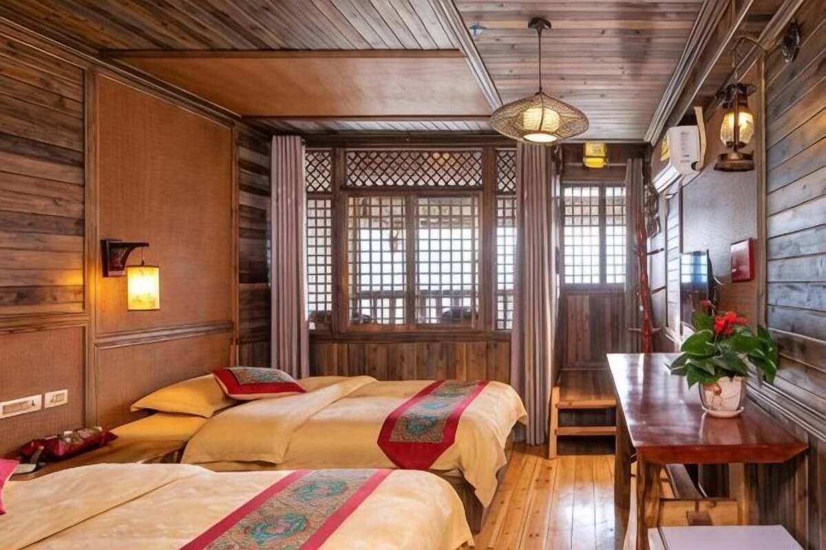 A traditional room with wooden walls and furniture, a window with a lattice design, and a table with a plant.