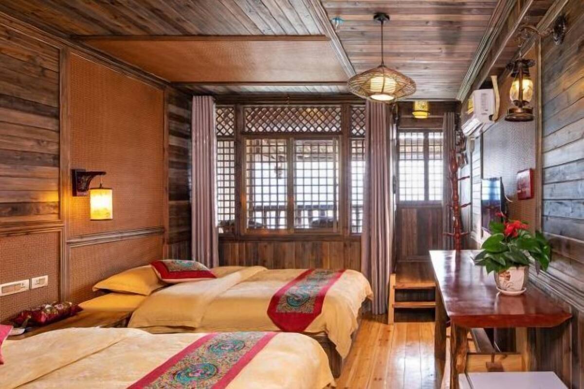 A traditional wooden room with two beds, a bench, and a table with a plant.