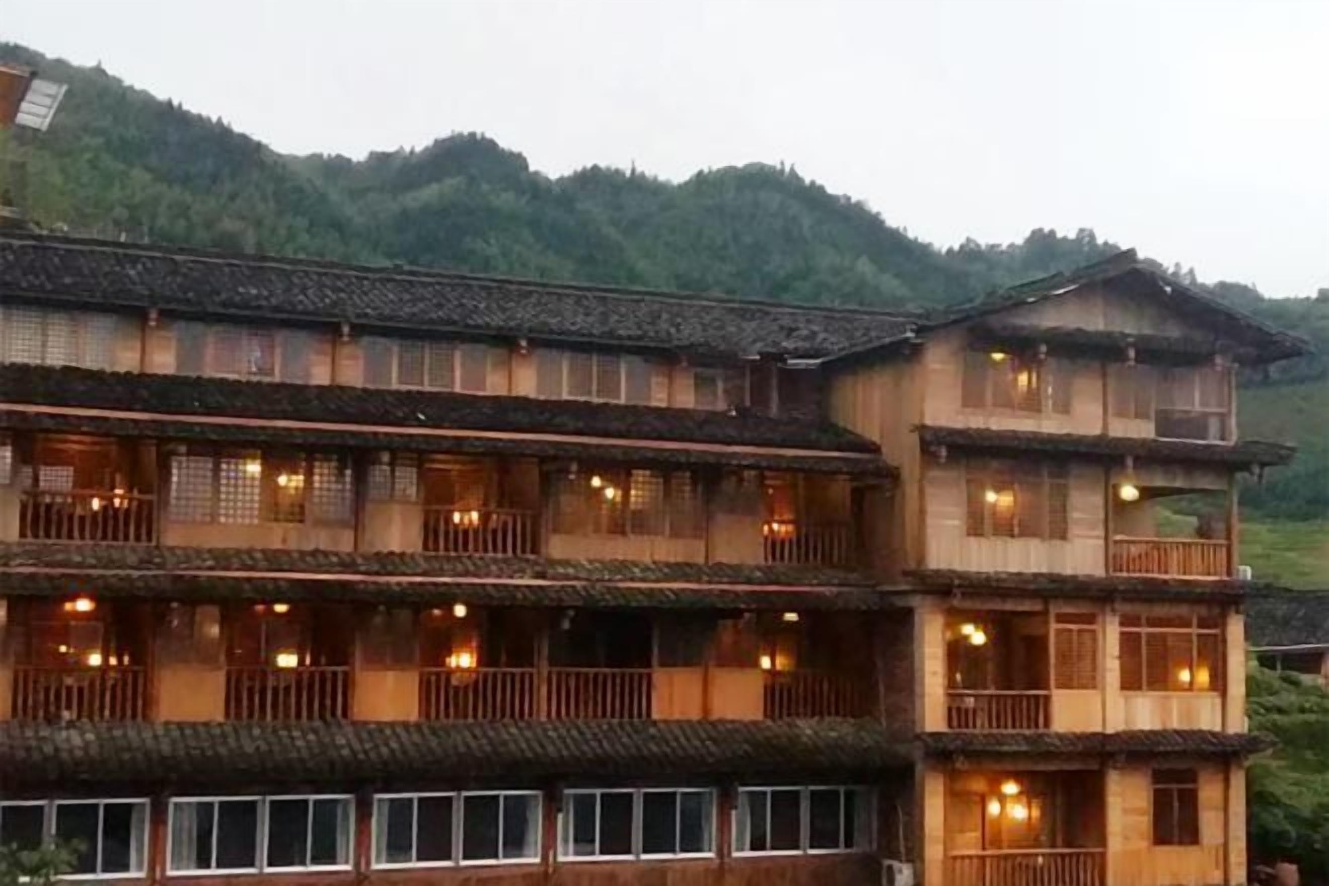 A traditional multi-story building with balconies and windows, surrounded by greenery.