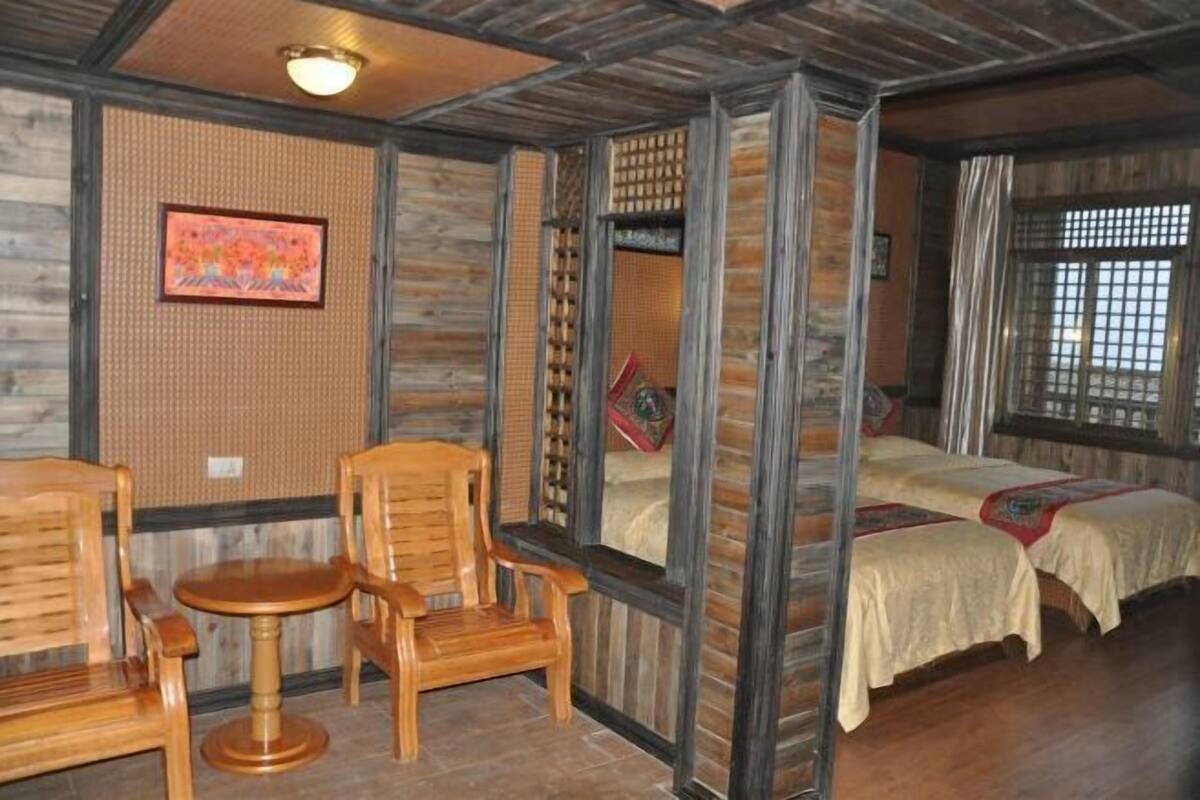 A traditional room with wooden furniture, a bed with a red pillow, and a window with a view.