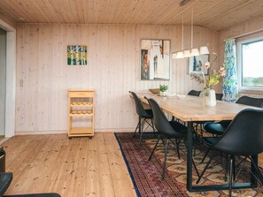 A dining area with a wooden table, black chairs, a rug, and a wooden wine rack.