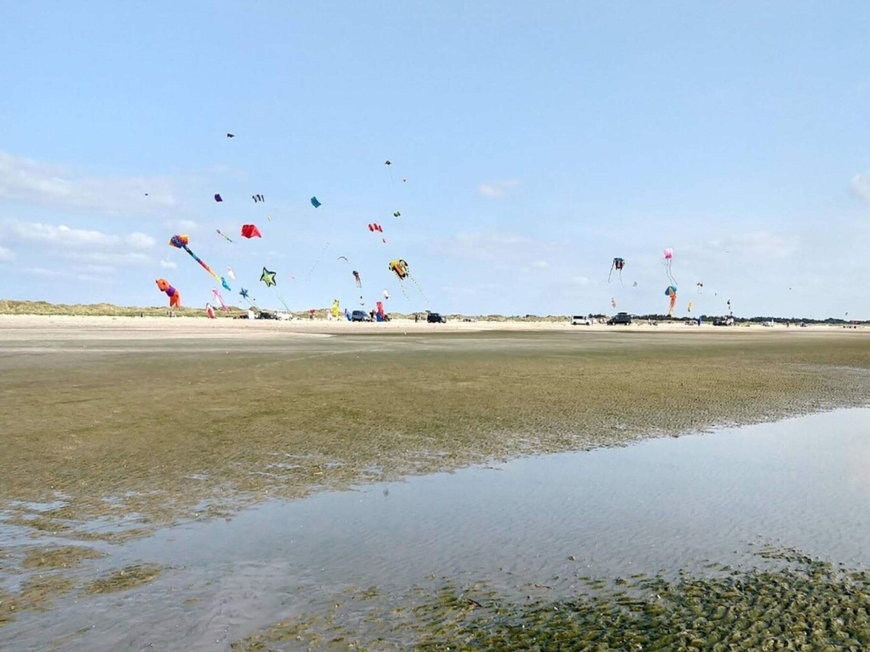 A beach with a wide expanse of sand and a shallow water area in the foreground.