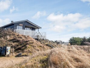 A building with a wooden exterior, a staircase leading to a deck, and a sign reading 'Kikkobjerg'. - 6 Person Holiday Home in Fano (Fano)