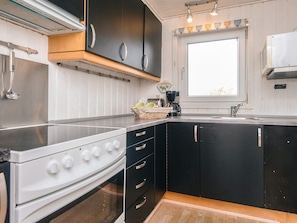 A modern kitchen with a stove, sink, and black cabinets.