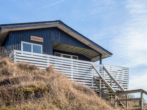 A wooden building with a sign reading 'Kikkeberg' and a white staircase leading up to a deck.