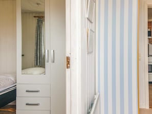 A bedroom with a bed, a wardrobe, and a door leading to a room with striped wallpaper. - 6 Person Holiday Home in Fano (Fano)