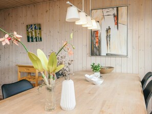 A wooden-paneled room with a dining table, chairs, a vase with flowers, a bowl, and a painting on the wall. - 6 Person Holiday Home in Fano (Fano)
