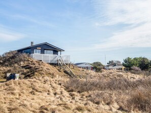 A coastal house with a wooden deck and stairs leading to the entrance. - 6 Person Holiday Home in Fano (Fano)