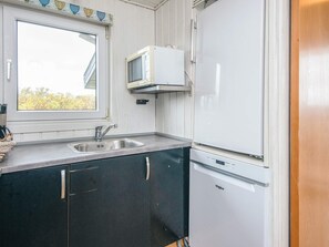A compact kitchen with a sink, a microwave, and a refrigerator. - 6 Person Holiday Home in Fano (Fano)