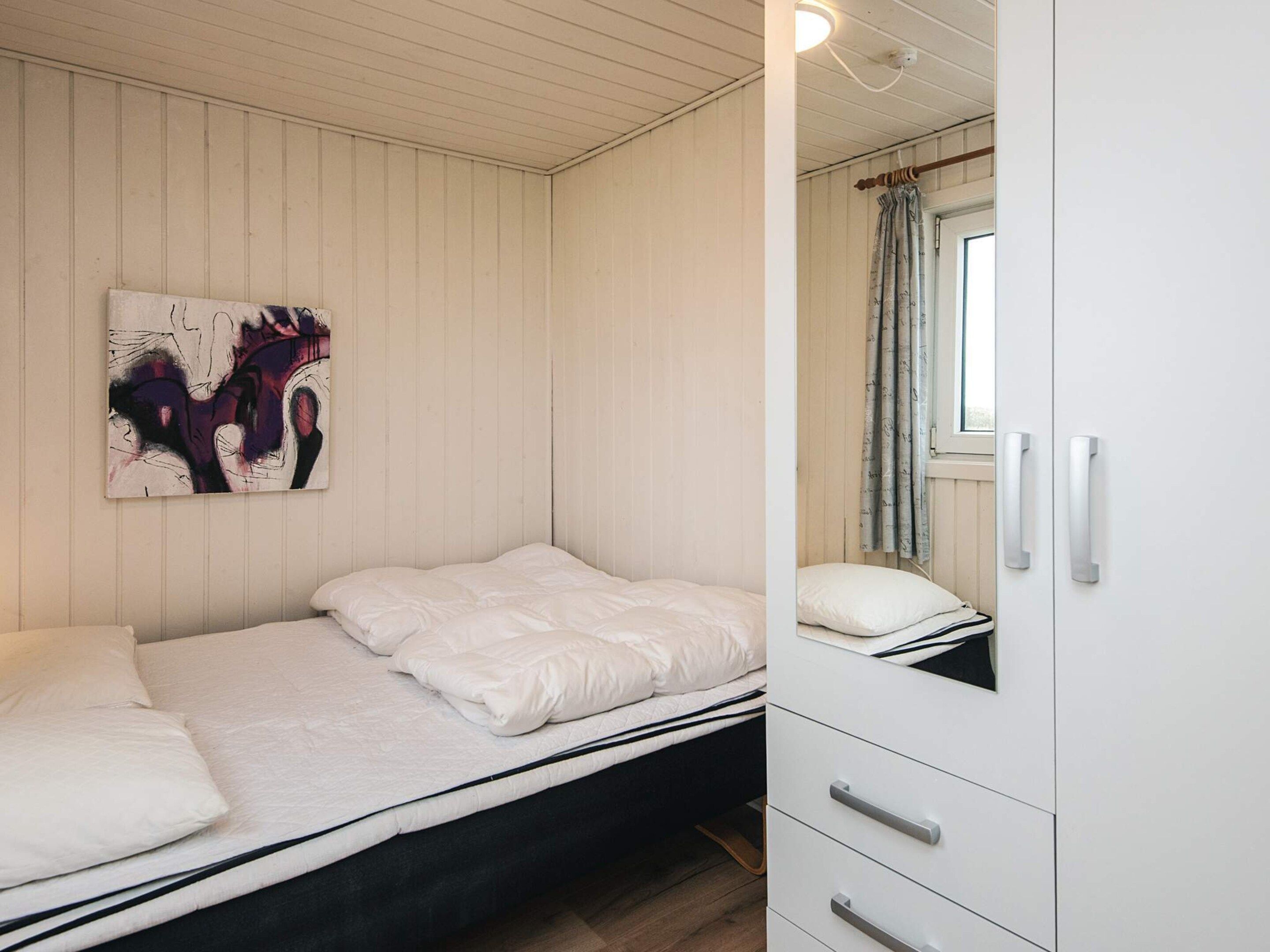 Une chambre à coucher avec un lit, une armoire et un tableau accroché au mur.