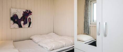 A bedroom with a bed, a wardrobe, and a painting on the wall.