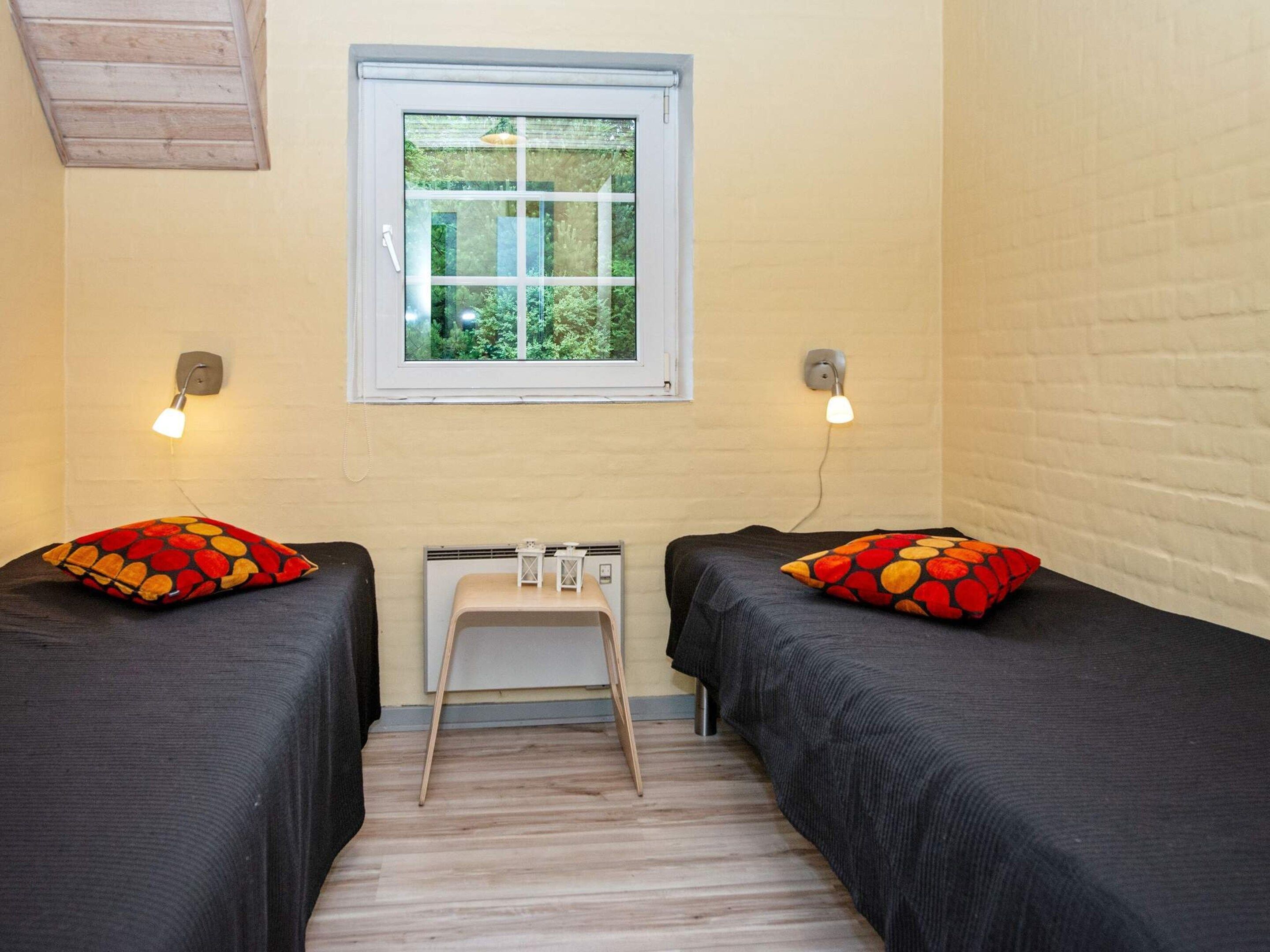 Una habitación con dos camas, una ventana y una pequeña mesa.