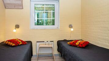 Una habitación con dos camas, una ventana y una pequeña mesa.