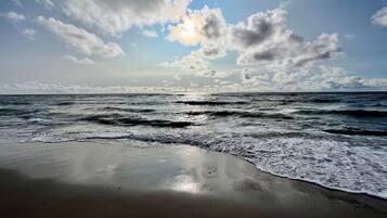 Una playa con olas y cielo parcialmente nublado.