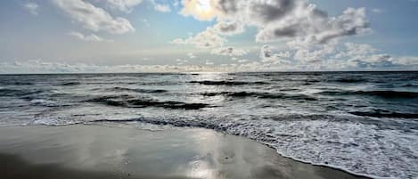 Uma praia com ondas e céu parcialmente nublado.