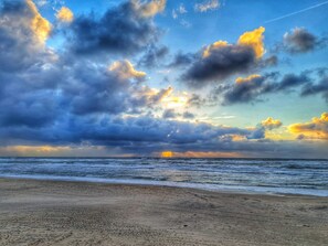 Une plage avec des vagues, un ciel nuageux et un horizon bien visible.