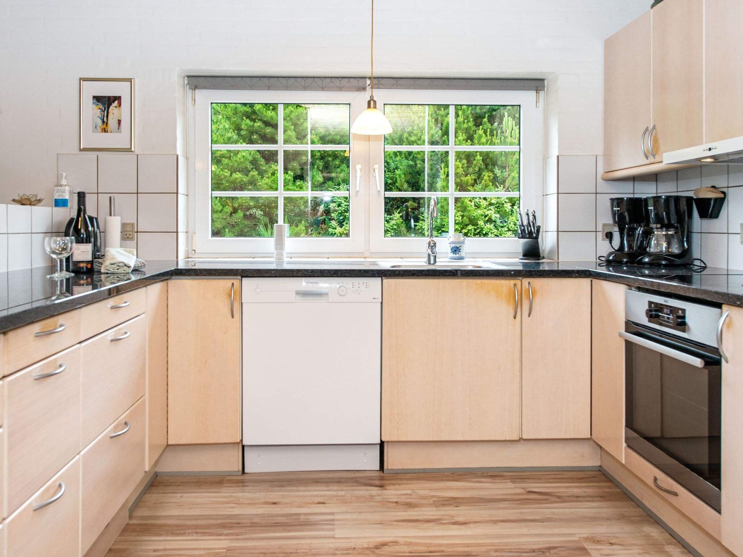 A modern kitchen with a dishwasher, oven, and coffee maker.