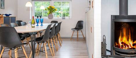 A modern dining area with a wooden table, black chairs, and a large window with a view of greenery.