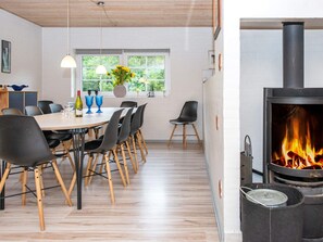 Un comedor moderno con una mesa de madera, sillas negras y un amplio ventanal con vistas a la vegetación.