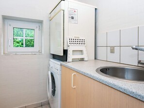 A compact kitchen with a washing machine, a small refrigerator, a sink, and a window with a view of greenery. - 12 Person Holiday Home in Ulfborg (Ulfborg)