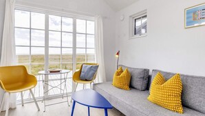 Un salon moderne comprenant un canapé, deux fauteuils, une petite table et une vue sur l’extérieur.
