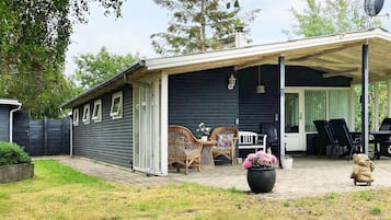 Un patio cubierto con muebles de exterior, una planta en maceta y una estatua.
