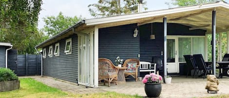 A covered patio area with outdoor furniture, a potted plant, and a statue.