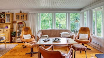 A cozy living room with a wooden floor, a beige sofa, leather armchairs, and a coffee table.
