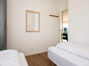 A bedroom with a wooden-framed mirror, a white bed, and a wooden floor. - 5 Star Holiday Home in Ansager (Ansager)