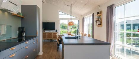 Una cocina moderna con una isla central, electrodomésticos integrados y un comedor con vistas al exterior.