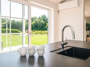 A modern kitchen with a large window, a stainless steel sink, and a built-in dishwasher. - 5 Star Holiday Home in Ansager (Ansager)