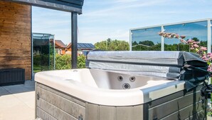 A hot tub in an outdoor setting with a wooden deck and a glass enclosure. - 5 Star Holiday Home in Ansager (Ansager)