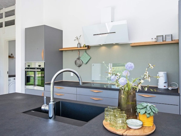 Una cocina moderna con horno empotrado, pileta de acero inoxidable y encimera de madera.