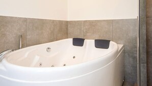 A large, white freestanding bathtub in a bathroom with tiled walls and a glass shower door. - 5 Star Holiday Home in Ansager (Ansager)