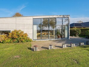 Un bâtiment moderne doté de grandes fenêtres en verre, d’une cour pavée et d’une pelouse bien entretenue.