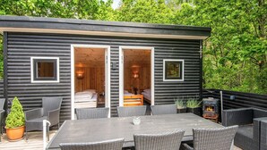 A log cabin with two bedrooms, a deck with wicker furniture, and a wood-burning stove.