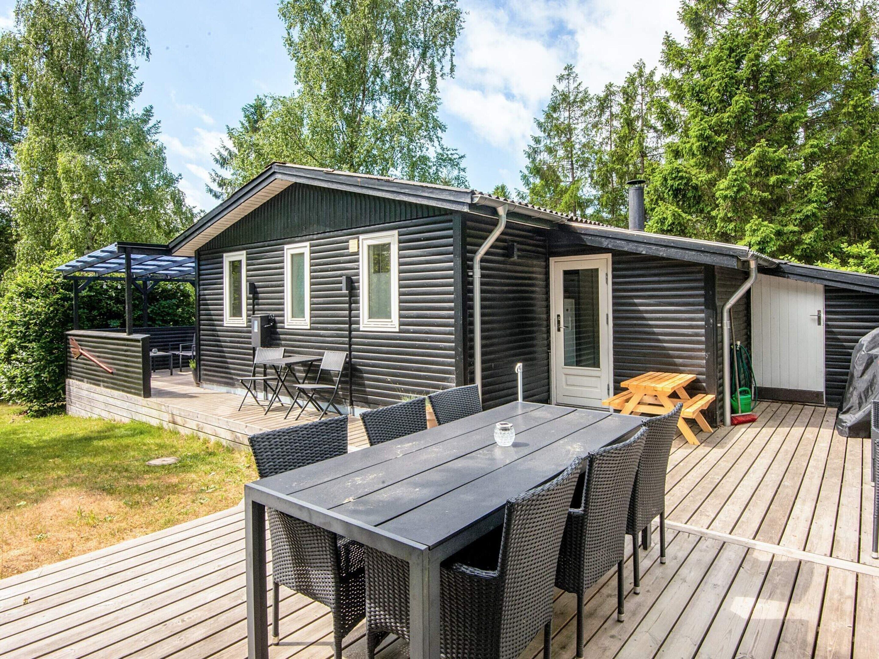 Eine Hütte mit einer Terrasse, einem Tisch und Stühlen.