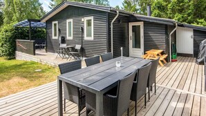 A cabin with a deck, a table, and chairs. - 8 Person Holiday Home in Ebeltoft (Ebeltoft)