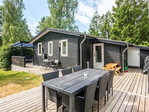 A cabin with a deck, a table, and chairs. - 8 Person Holiday Home in Ebeltoft (Ebeltoft)