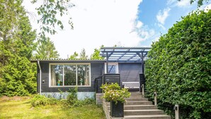 A cabin with a porch, steps, and a window overlooking a garden. - 8 Person Holiday Home in Ebeltoft (Ebeltoft)