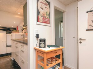 A modern kitchen with white cabinets, a wooden table with a radio, and a Coca-Cola poster on the wall. - 8 Person Holiday Home in Ebeltoft (Ebeltoft)
