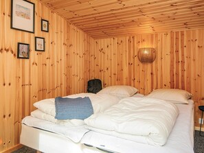 A wooden-paneled room with a bed, framed pictures on the wall, and a woven light fixture. - 8 Person Holiday Home in Ebeltoft (Ebeltoft)