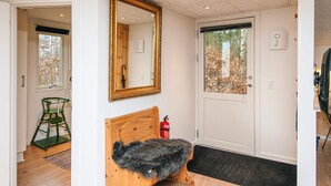 A room with a wooden bench, a large mirror, a door with a window, and a fire extinguisher.