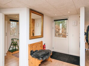 A room with a wooden bench, a large mirror, a door with a window, and a fire extinguisher. - 8 Person Holiday Home in Ebeltoft (Ebeltoft)