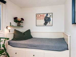 A room with a bed, a wall-mounted shelf with flowers, and a poster. - 8 Person Holiday Home in Ebeltoft (Ebeltoft)