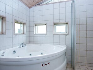 A bathroom with a large white bathtub, three small windows, and tiled walls. - 4 Star Holiday Home in Juelsminde (Horsens)