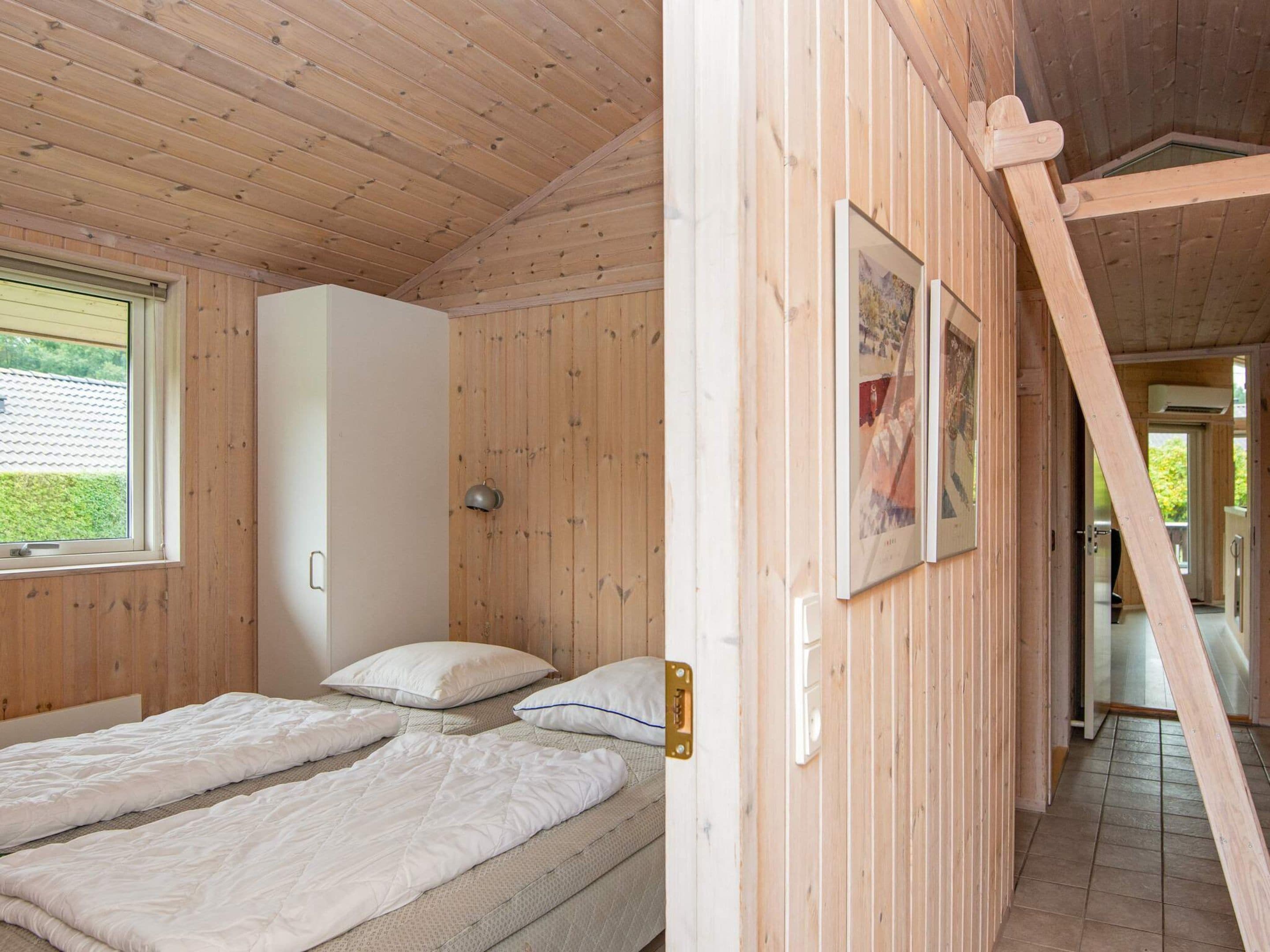A wooden interior with a bed, a white wardrobe, and a door leading to another room.